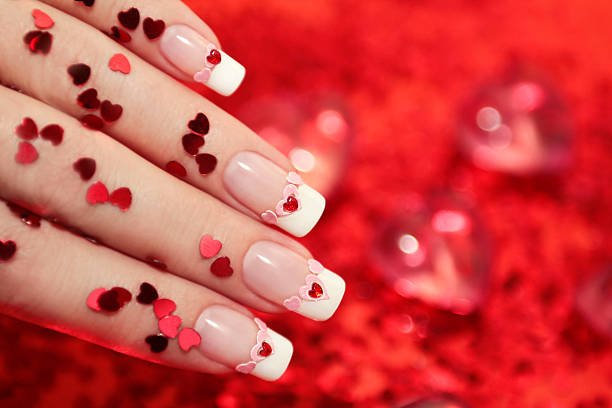 Well-kept manicure with sequins and rhinestones in the form of hearts.