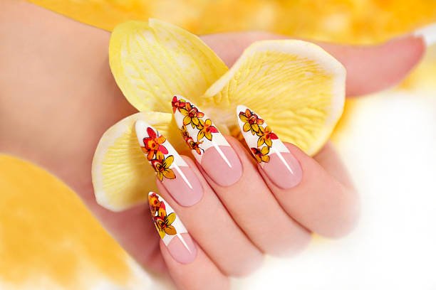 Nail with a pattern of yellow orchids on a long shaped nails.