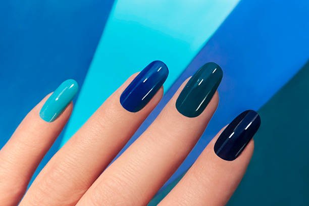 Blue manicure in light and dark colors of lacquer on a striped background.