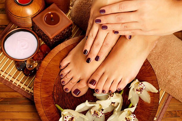 Closeup photo of a female feet at spa salon on pedicure procedure. Female legs in water decoration  the flowers.