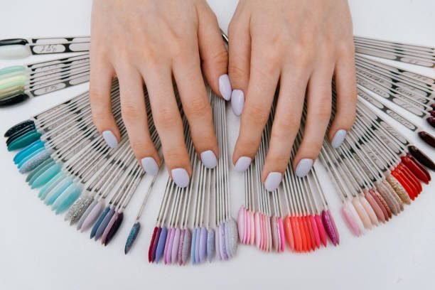 Close-up hands of manicurist professional woman in a blue rubber gloves is choose a palette of colors nail polish